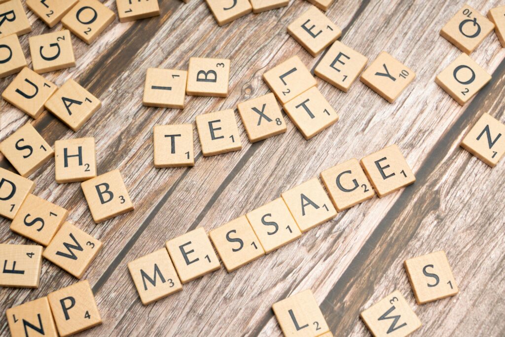 Scrabble tiles spelling 'text message' on a wooden background, ideal for communication themes.